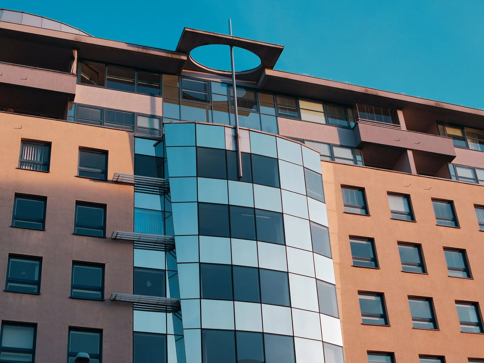 Close-up of a modern urban building facade with geometric design and reflective windows in sunlight.